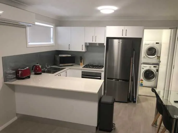Apartment kitchen with stacked washer dryer, full fridge and gas cooktop