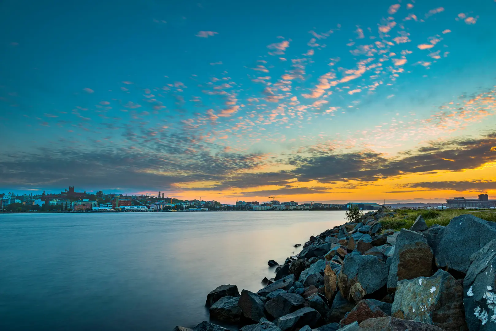 Sunset over Newcastle Harbour with the city skyline reflected in calm water